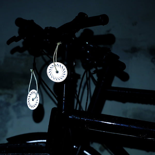 refleks vedhæng på cykel der lyser i mørket og øger synlighed i trafikken
