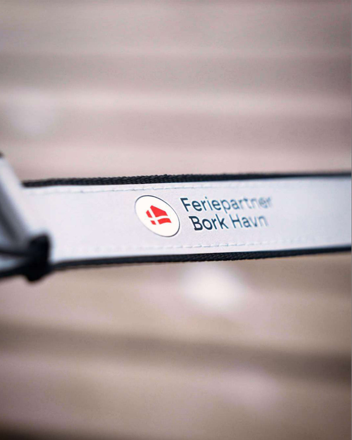 Reflekterende Safe & Shine Comet Strap med Feriepartner Bork Havn logo til øget synlighed.