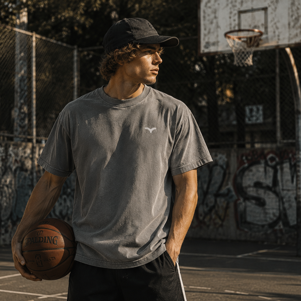 Person iført grå Endless Hope T-shirt med lille reflekslogo på brystet. T-shirten er fotograferet på en basketballbane og kombinerer komfort, bevægelsesfrihed og et minimalistisk design.