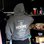 Grå hoodie med stort HOPE refleksprint og fyrtårnsmotiv set bagfra