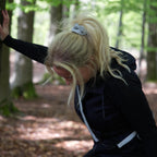 Kvinde i skoven med refleks-scrunchie fra Safe & Shine i håret – funktionel accessory til aktivitet, natur og hverdag