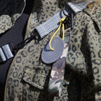 Refleksvedhæng fra Safe & Shine fastgjort på taske med gul refleksnor og camouflage rem