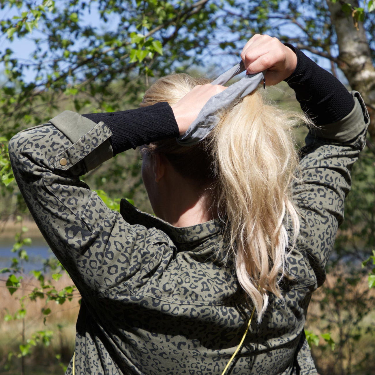 Kvinde sætter håret op med refleks-scrunchie fra Safe & Shine – funktionel håraccessory med synlighed til hverdag og outdoor