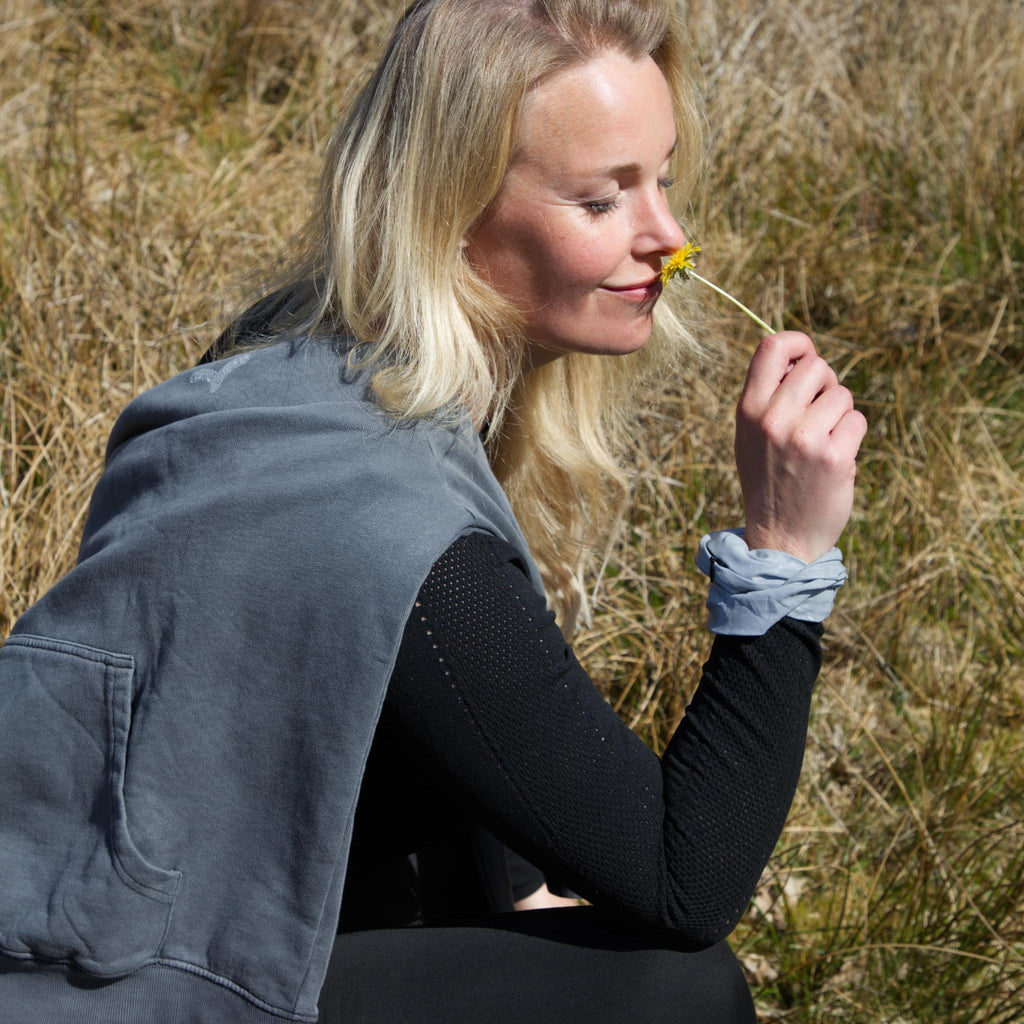 Kvinde i naturen med refleks-scrunchie fra Safe & Shine på håndleddet – funktionel accessory til hverdag og bevægelse