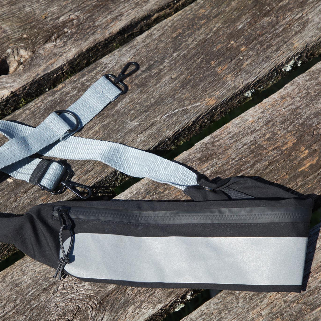 Sort crossbody taske med bred refleksdetalje og justerbar rem fra Safe & Shine – designet til øget synlighed i hverdagen