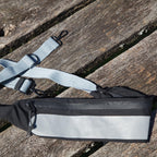 Sort crossbody taske med bred refleksdetalje og justerbar rem fra Safe & Shine – designet til øget synlighed i hverdagen