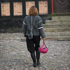 A person wearing a reflective bag strap that increases visibility in traffic during everyday life