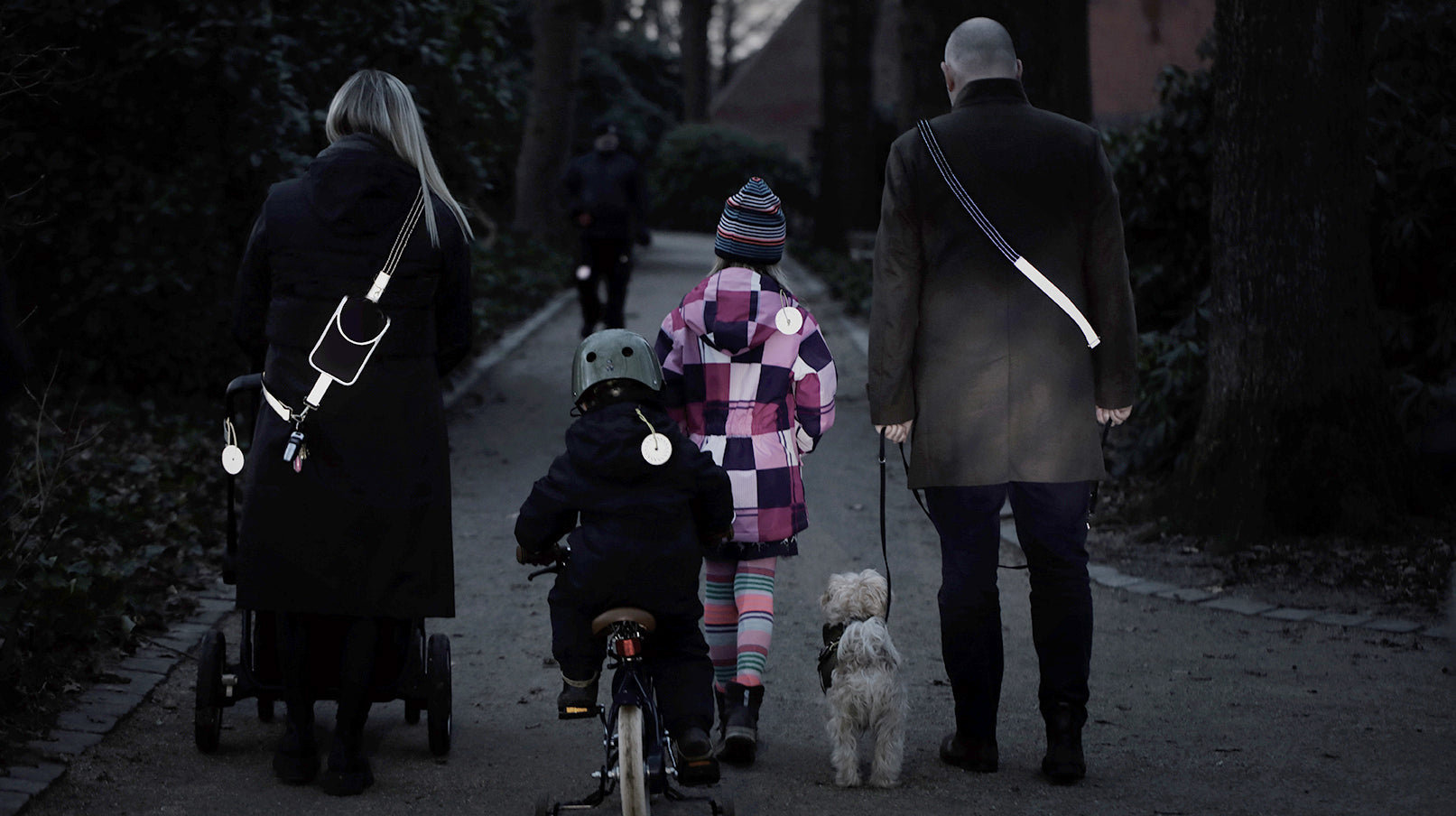 familie og hund med reflekser der øger synlighed i trafikken i mørke